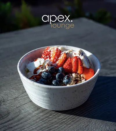 Granola bowl topped with strawberries and blueberries at Apex Lounge
