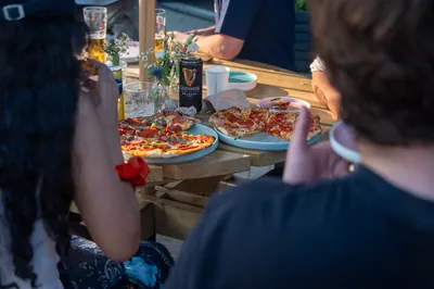Friends sharing pizzas and drinks at an Apex Lounge table