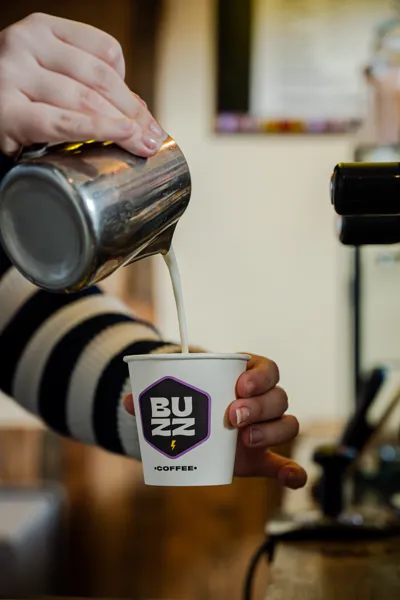 Milk being poured into a Buzz Coffee takeaway cup